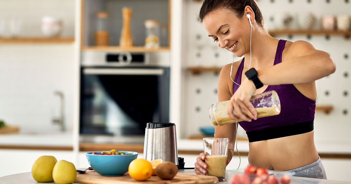 Frau bereitet einen Protein-Shake als schnelles proteinreiches Frühstück in der Küche zu